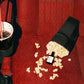 Popcorn and a bottle on a red movie theater seat with a cup of soda.