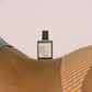 Perfume bottle labeled 'sea, sand & sun' by 'versatile' on a textured surface.