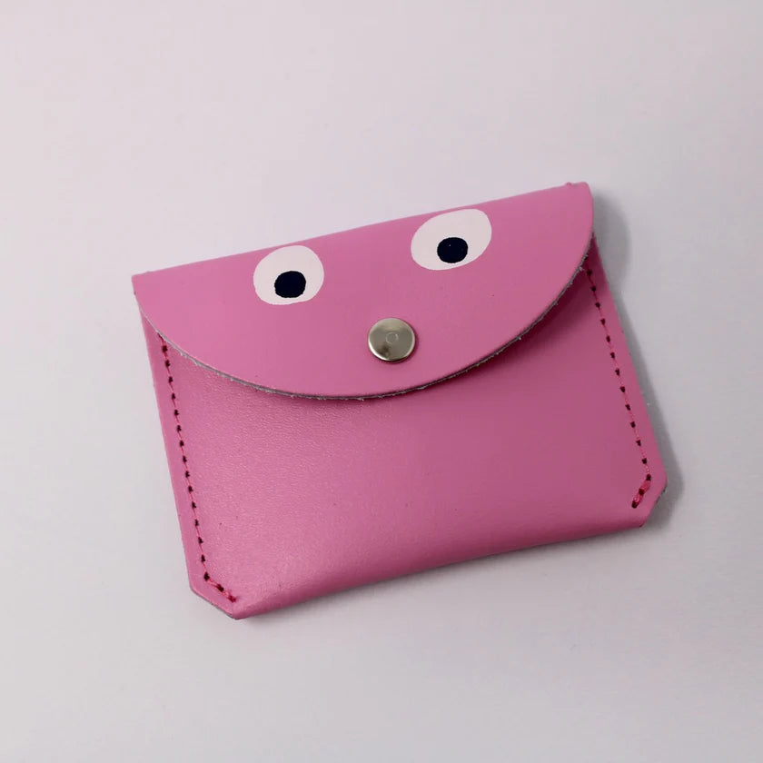 a rectangular ark colour design hot pink googly eye purse. It has a silver button. The background is white. 