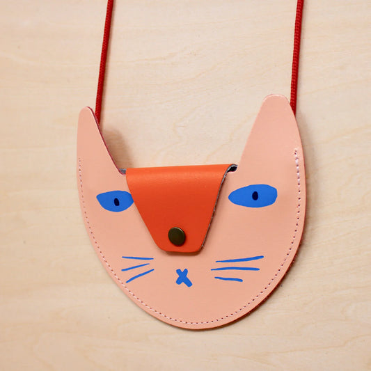 Ark colour design pale pink/orange cat pocket purse. The flap is orange with a silver button. The ears are pale pink. The eyes are blue in colour. The mouth and whiskers are blue in colour. It has a red string. The background is white