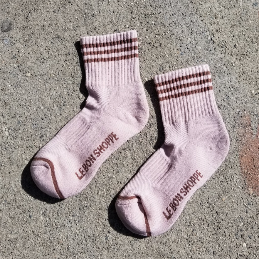 A close-up of Bellini pink ribbed crew socks with brown stripes, showing the thick ribbed texture, cushioned heel, and Le Bon Shoppe branding on the sole.