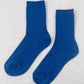 A pair of cobalt blue ribbed crew socks laid flat on a white background, showing their texture and design.
