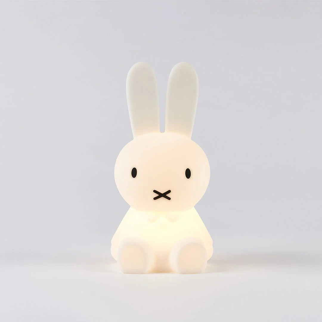 A white Miffy First Light Lamp with a soft glow, shaped like a rabbit with long ears and a simple black-lined face, sitting against a plain background.