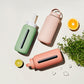 A matte Silicone covered glass bottle, with a window to see the drink on the inside, in a pinky cream colour with a plastic screw top circular lid with a handle