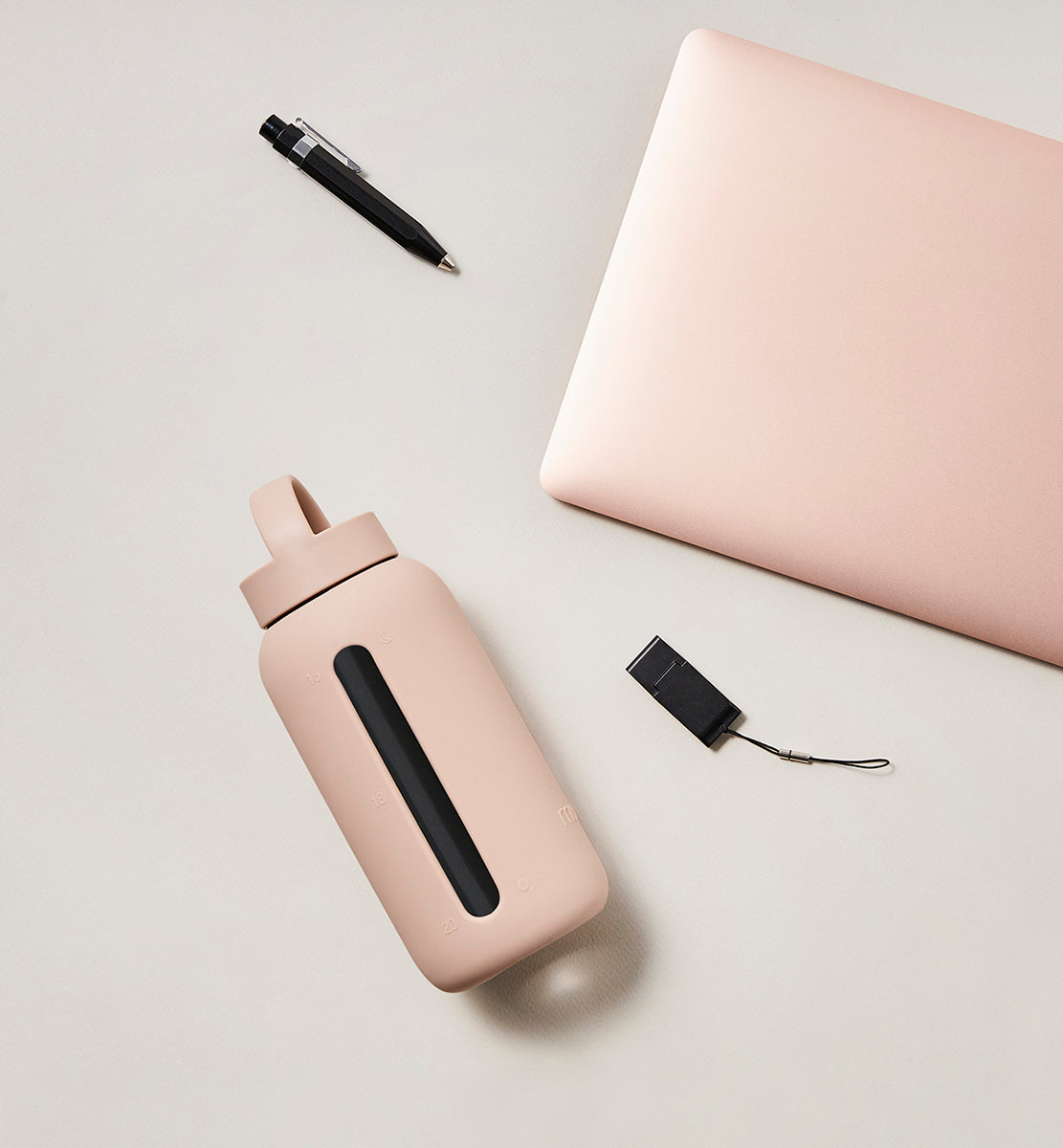 A matte Silicone covered glass bottle, with a window to see the drink on the inside, in a pinky cream colour with a plastic screw top circular lid with a handle
