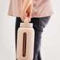 A matte Silicone covered glass bottle, with a window to see the drink on the inside, in a pinky cream colour with a plastic screw top circular lid with a handle