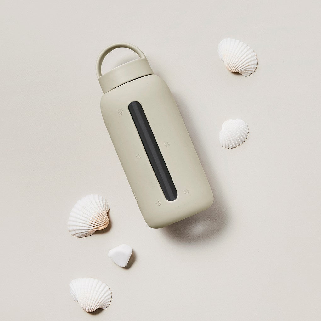 A matte Silicone covered glass bottle, with a window to see the drink on the inside, in a creamy white colour with a plastic screw top circular lid with a handle
