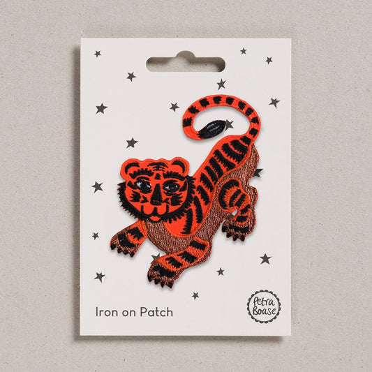 an embroidered orange crouching tiger with black stripes. The background is white with black stars. 