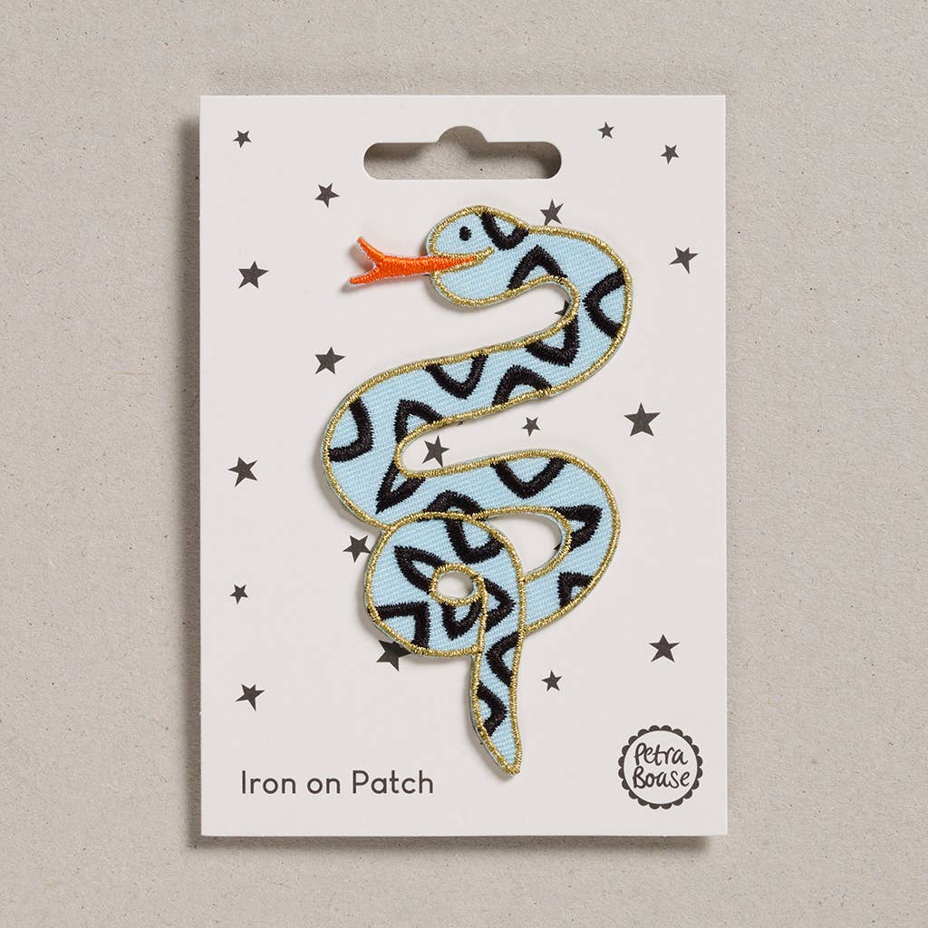  an embroidered snake which is light blue in colour with orange tongue. Its body has black triangles and golden border. The background is white with black stars. 