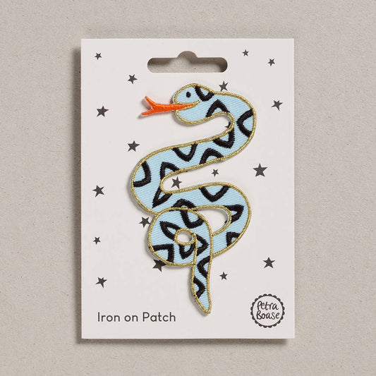  an embroidered snake which is light blue in colour with orange tongue. Its body has black triangles and golden border. The background is white with black stars. 
