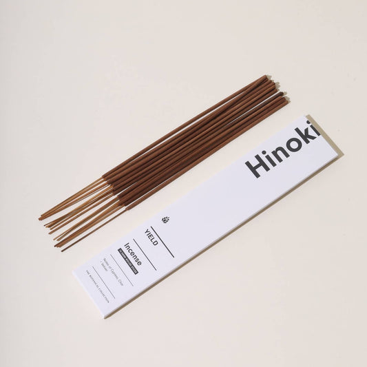 The box is white with writing in a modern black font. 15 incense sticks lay next to the box on a plain cream background. 